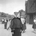 Sister Helaine, eighth grade teacher in room 211, suffered severe burns as a result of the fire. Here, she is seen standing on Avers Avenue several years before the fire. The door at right leads to a stairway into the basement of the south wing. (Photo courtesy of Class of 1956 Reunion Committee)
